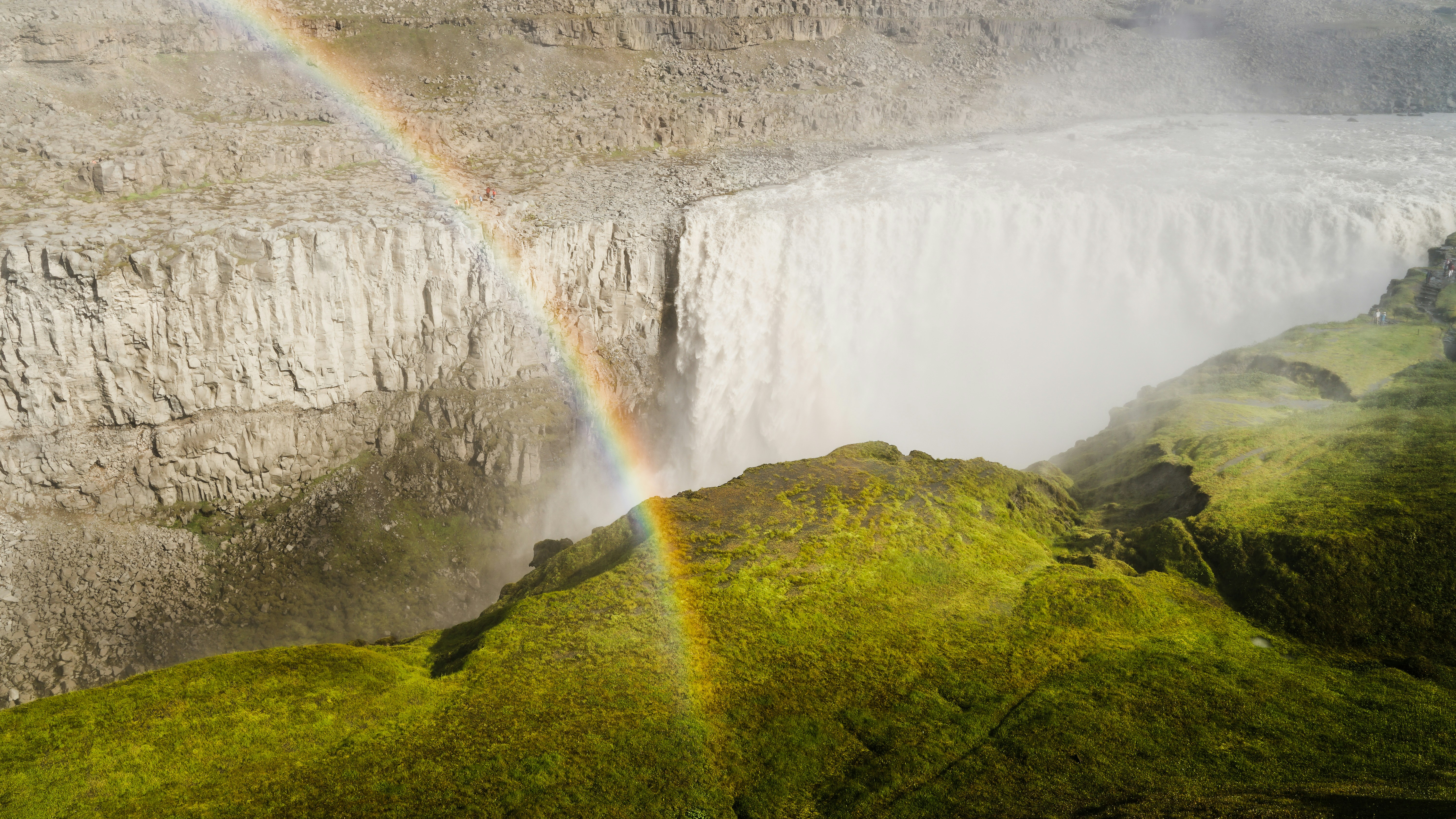 a rainbow in the sky over a waterfall