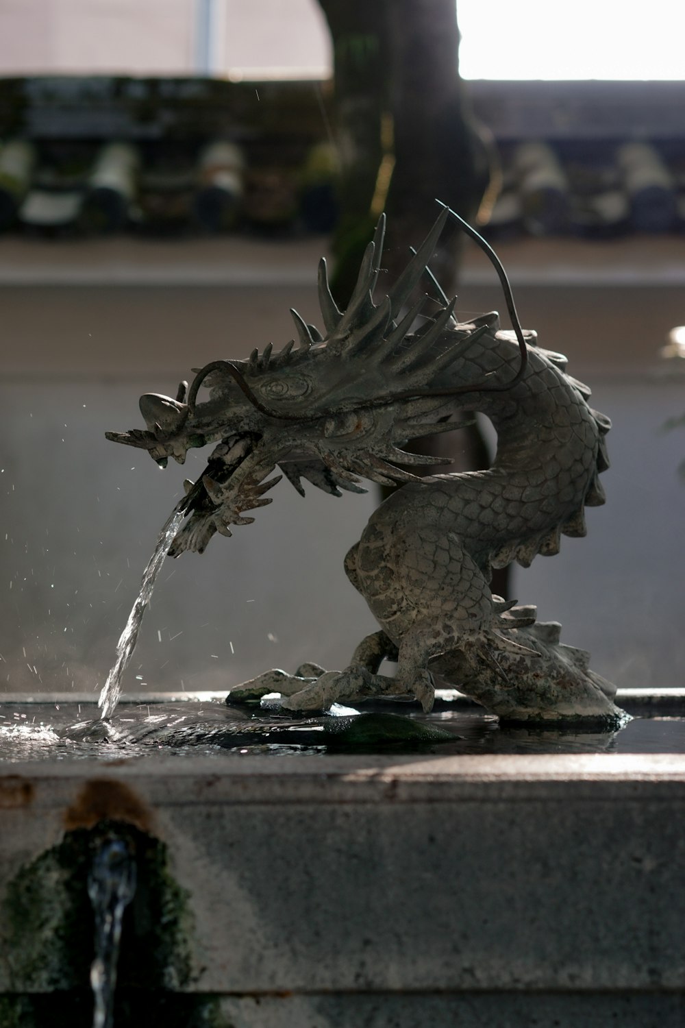 a statue of a dragon drinking water from a fountain