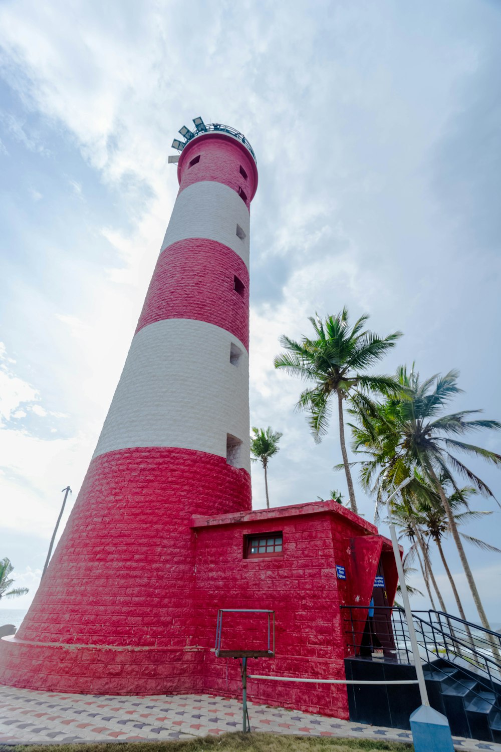 a large red and white lighthouse next to a palm tree