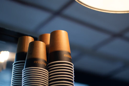 Stacks of eco-friendly paper cups drying under natural sunlight surrounded by green plants.