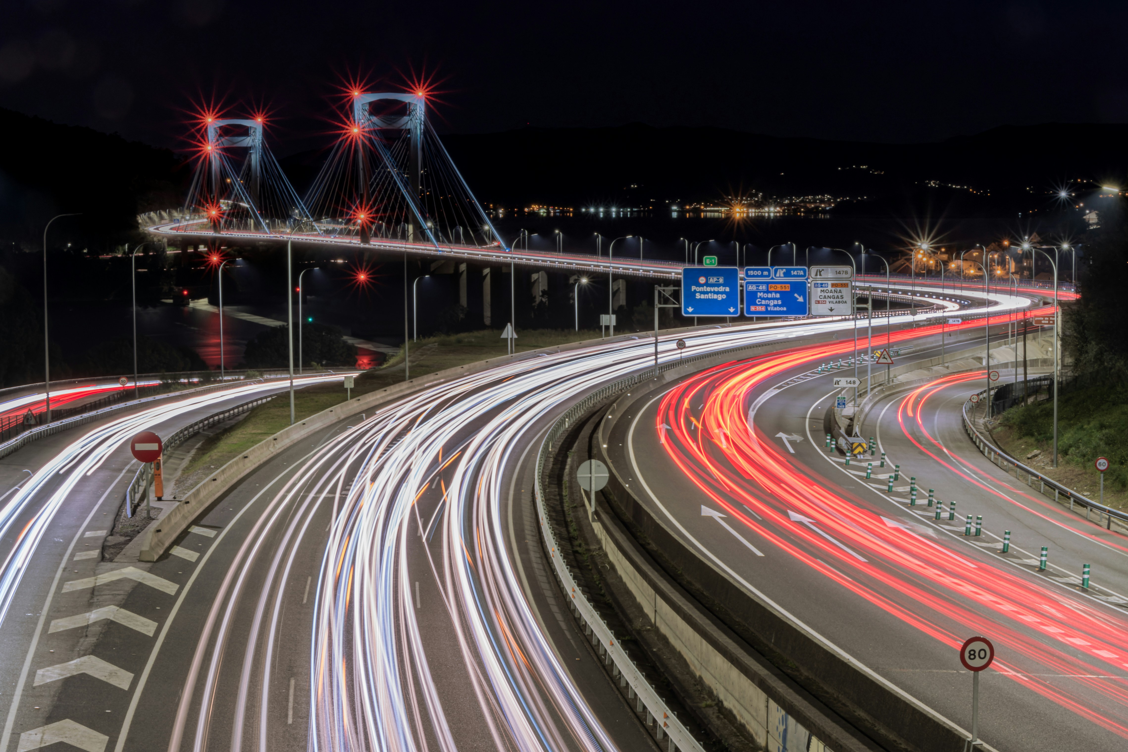 Un'immagine notturna di un'autostrada con un ponte sullo sfondo