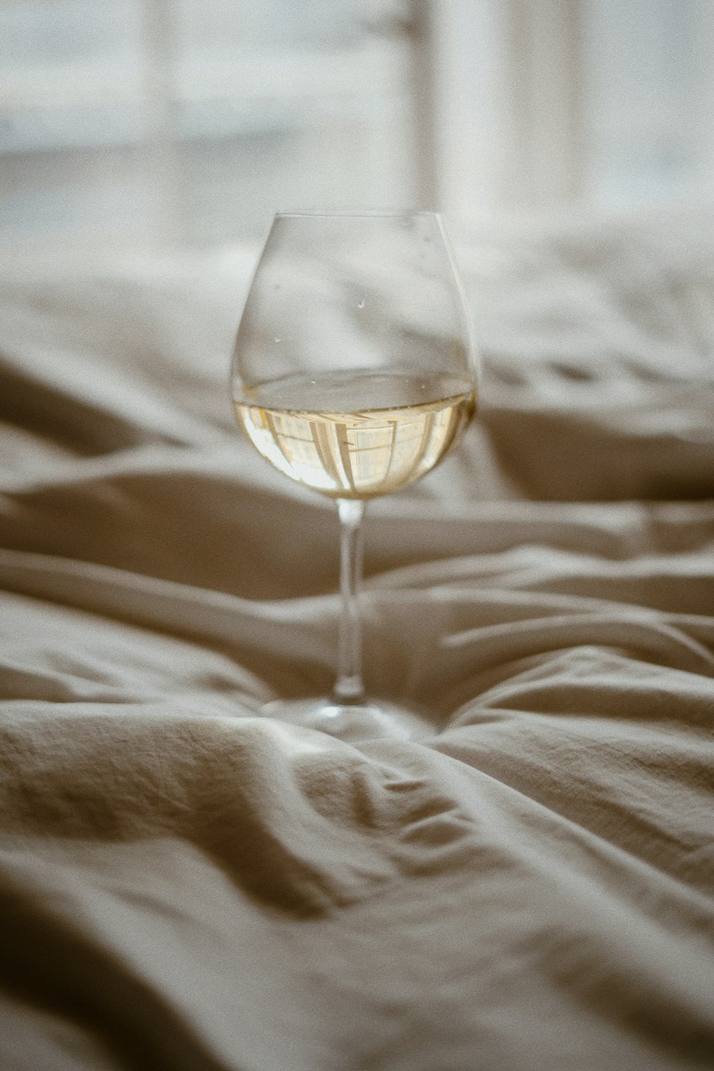 a glass of wine sitting on top of a bed
