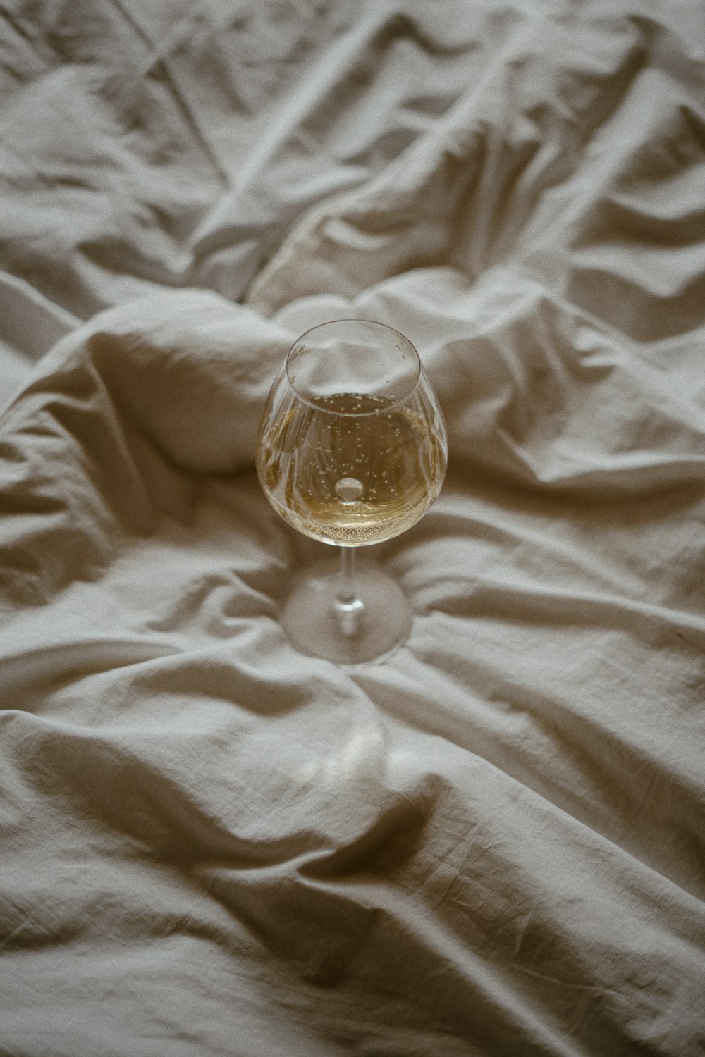a glass of wine sitting on top of a bed