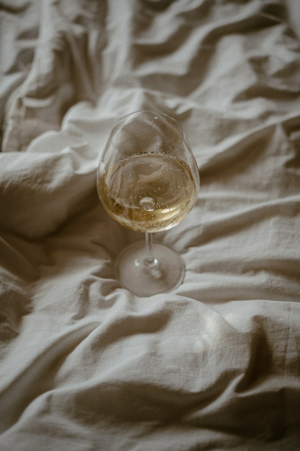 un bicchiere di vino seduto sopra un letto