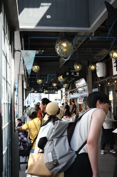A bustling market street with a traveler calculating expenses while browsing vibrant stalls.