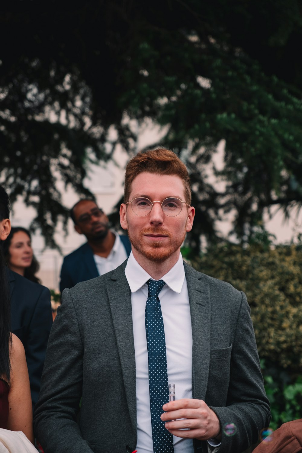 a man in a suit and tie standing in front of a group of people