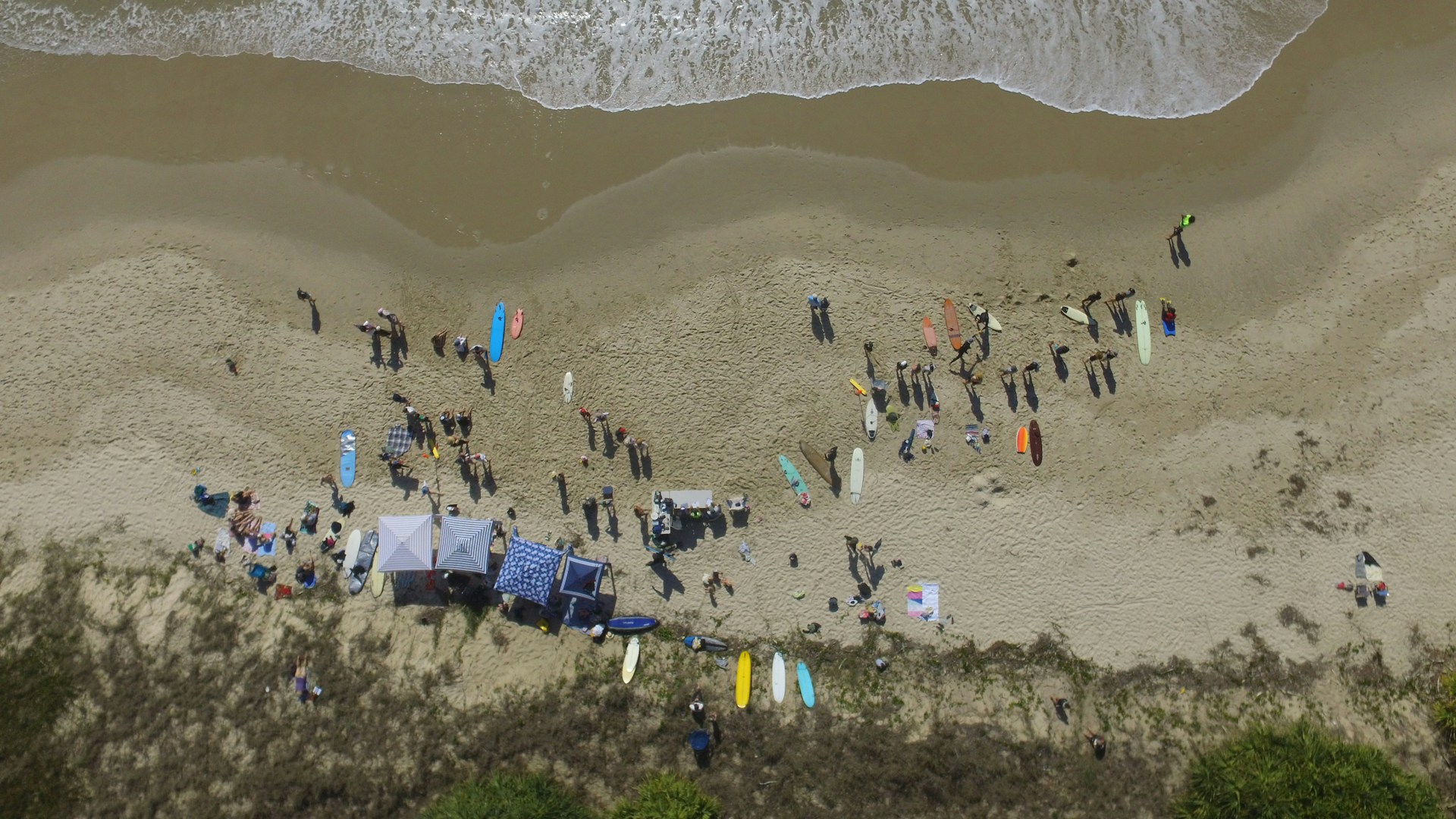 A stunning overhead perspective of a coastal event in Essex, featuring colorful tents and a lively crowd on the beach.