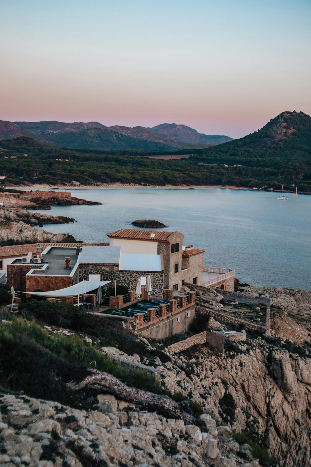 a large building sitting on top of a rocky hill next to a body of water