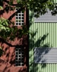 a green building with two windows and a tree in front of it