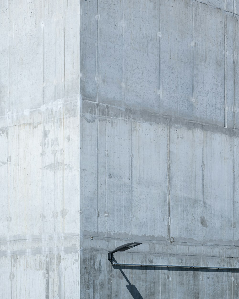 a man with a surfboard standing in front of a concrete wall