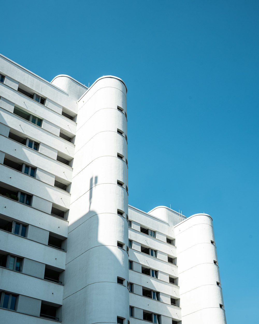 um edifício branco alto sentado ao lado de um céu azul