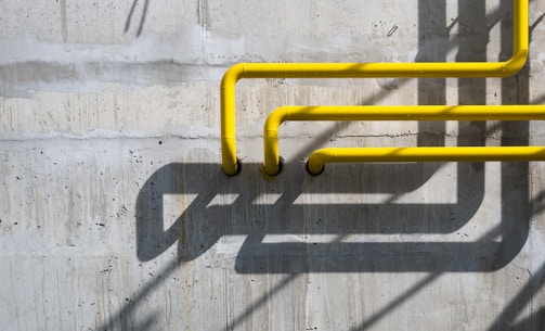 a yellow pipe on the side of a concrete wall