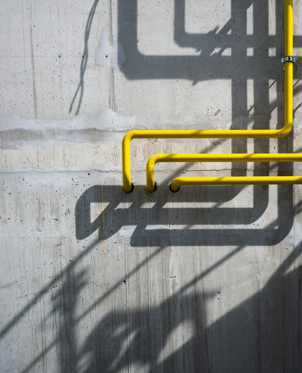 a yellow pipe on the side of a concrete wall