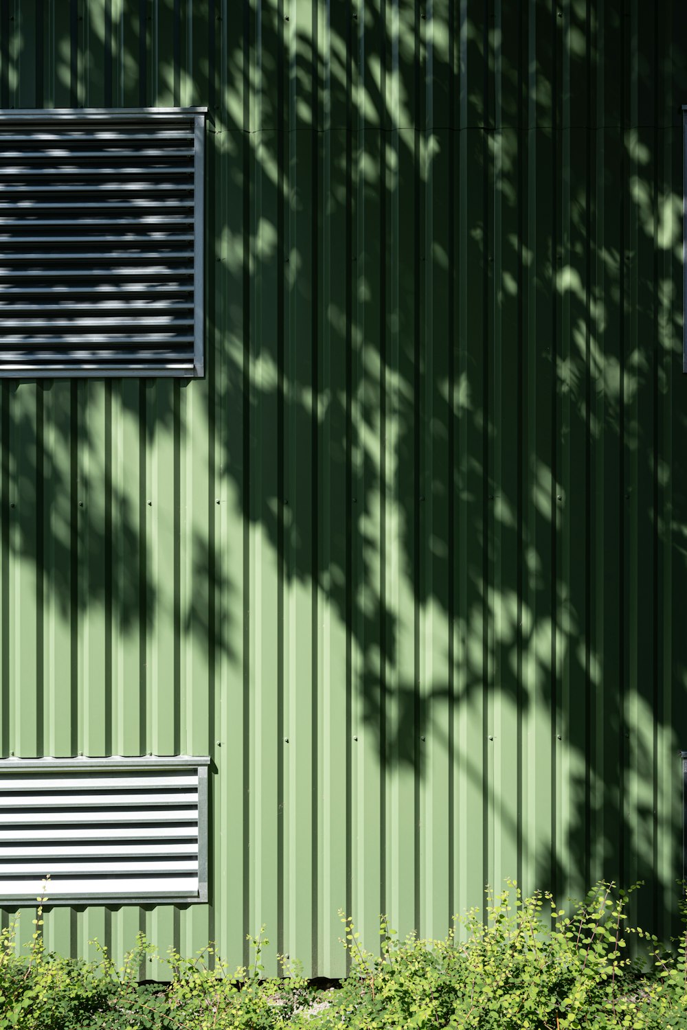 a green building with a window and a bench