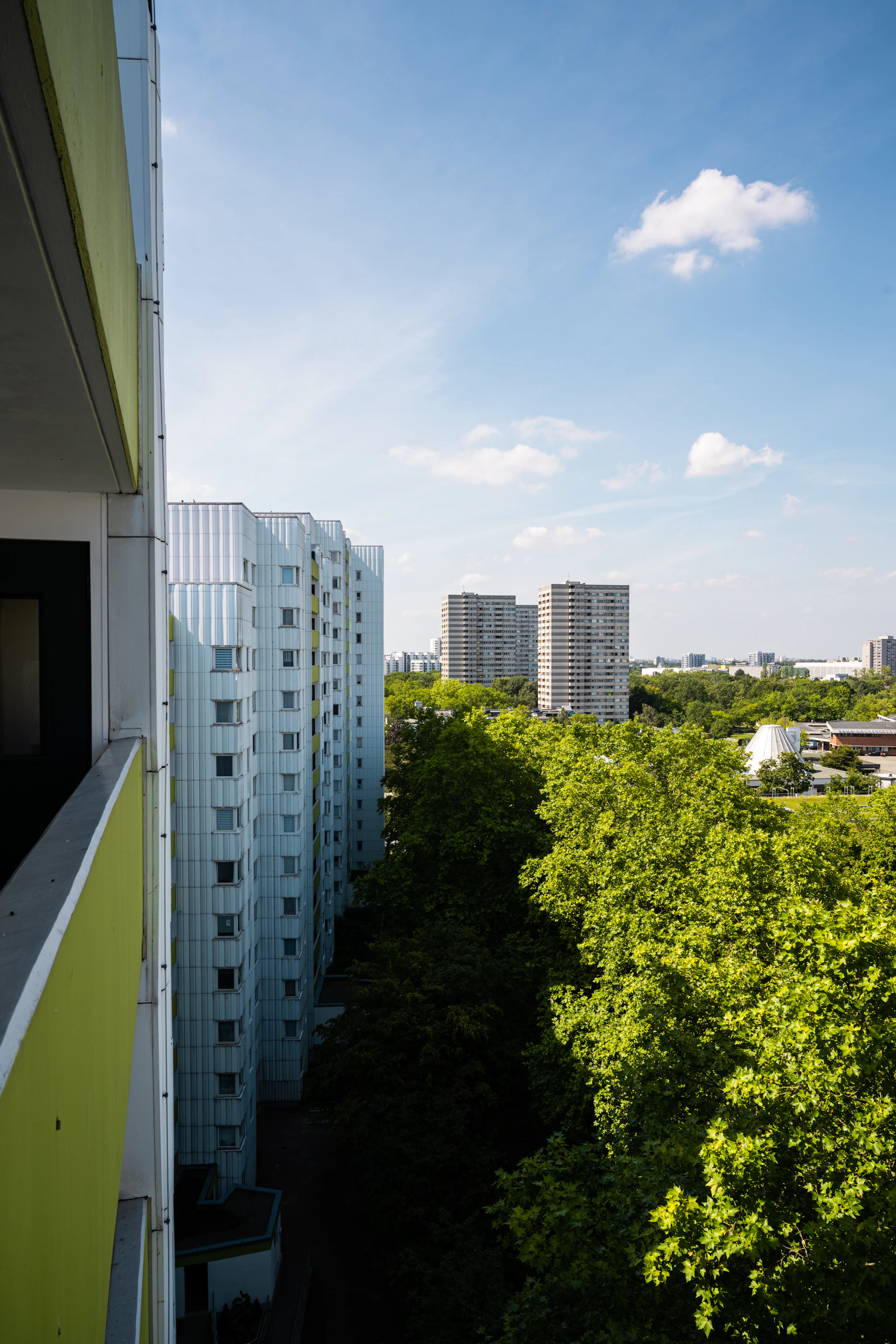 A serene early morning view of a modern residential condominium with soft pastel tones and lush greenery.
