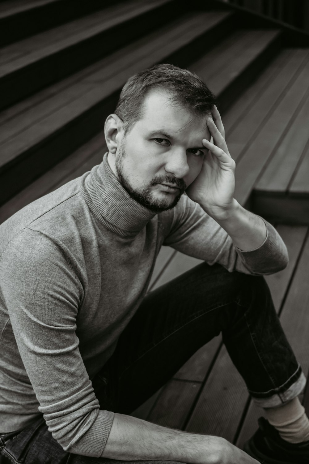 a black and white photo of a man sitting on a deck