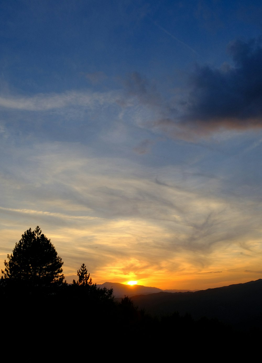 the sun is setting over the mountains and trees