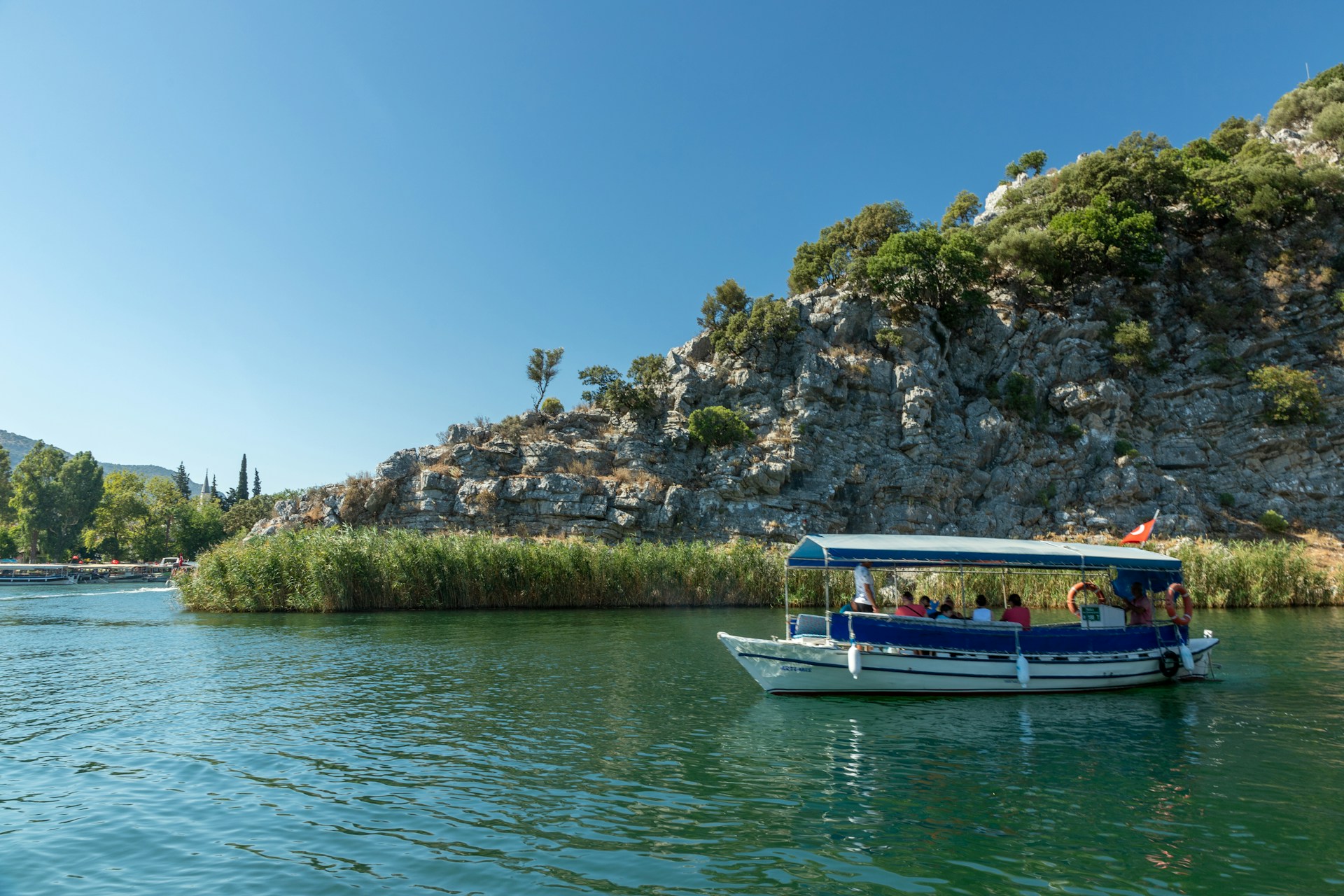 a boat is on the water near a cliff