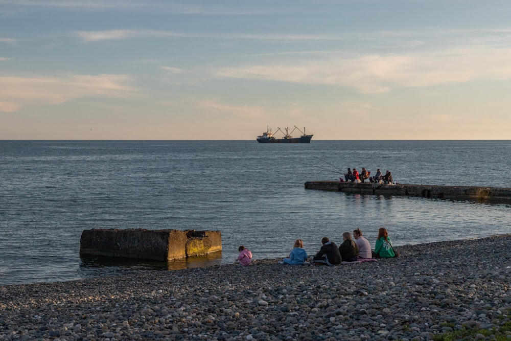 a group of people sitting on a beach next to the ocean