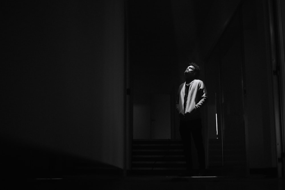 a man standing in a dark hallway with his hands in his pockets