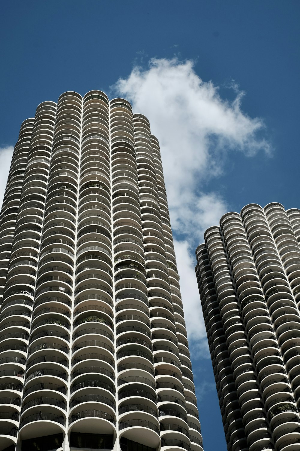 two tall buildings with circular balconies against a blue sky