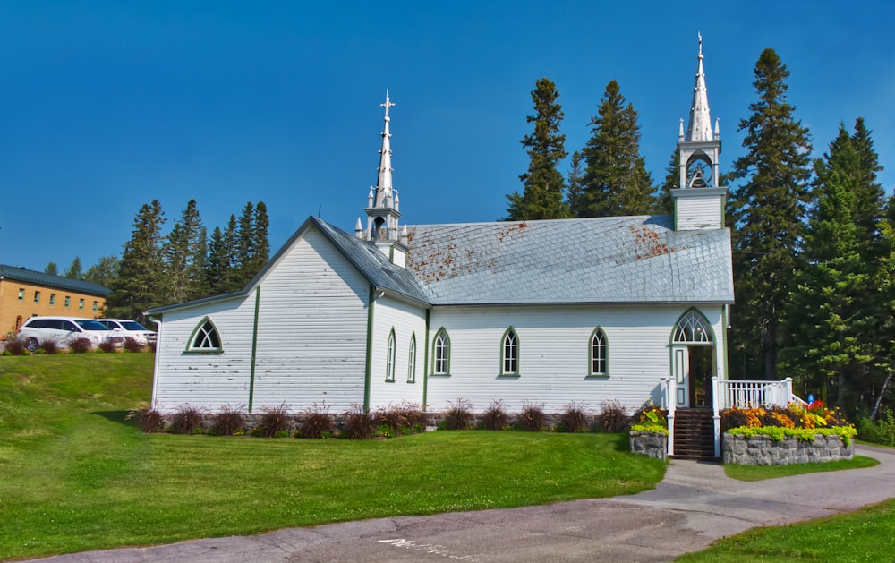 a white church with a steeple and flowers in front of it