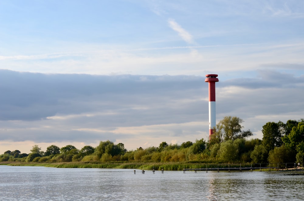 a large body of water with a red and white tower in the background