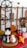 A collection of decorative items arranged on a red surface, featuring various ceramic vases, a wooden heart-shaped plaque, and intricately carved wooden panels depicting a man's face and a horse. There are also industrial-style cog wheels and dried floral arrangements.