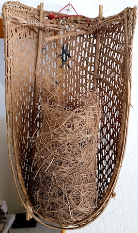 Rustic wooden basket filled with bundles of natural fibers ready for processing.