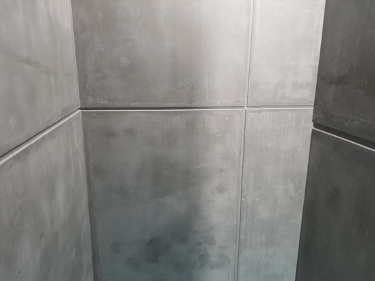 A minimalist space with smooth, grey concrete walls creating a sharp, geometric pattern. The clean lines and uniform texture give a modern, industrial appearance.