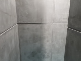 A minimalist space with smooth, grey concrete walls creating a sharp, geometric pattern. The clean lines and uniform texture give a modern, industrial appearance.