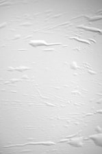 Close-up of a white textured surface with subtle shadows creating depth.