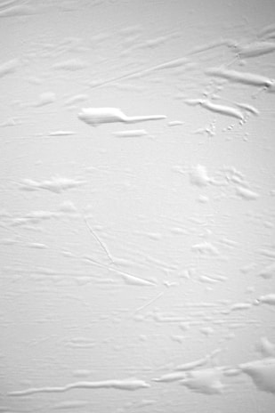 Close-up of a white textured surface with subtle shadows creating depth.