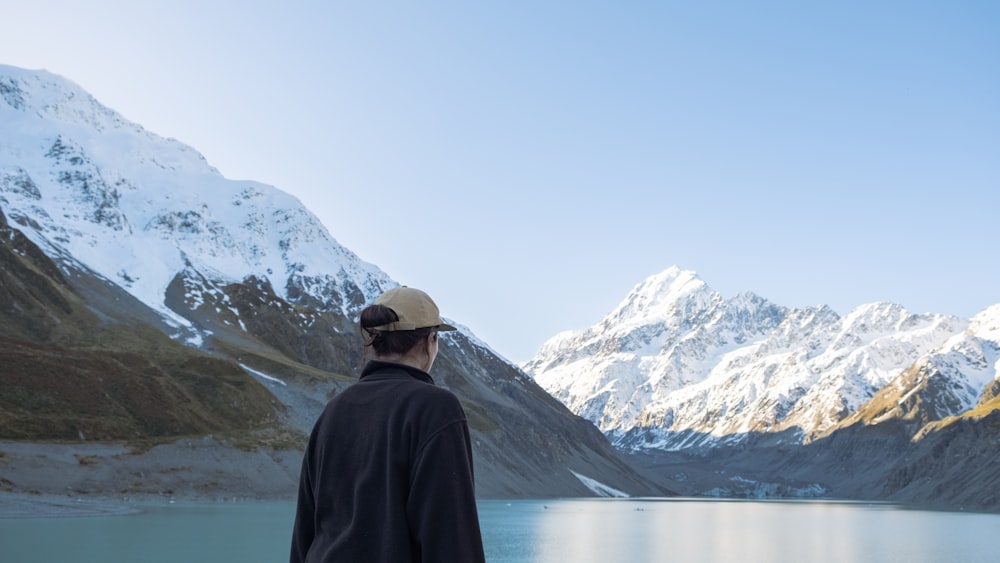 a man standing in front of a mountain lake