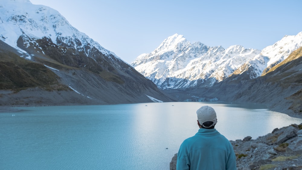 a man standing in front of a mountain lake
