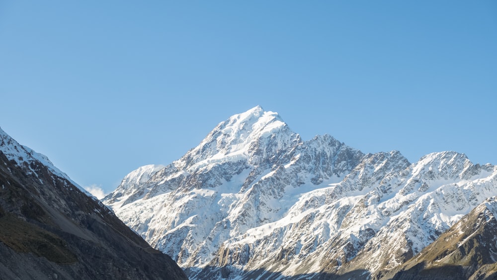 a mountain range covered in snow under a blue sky