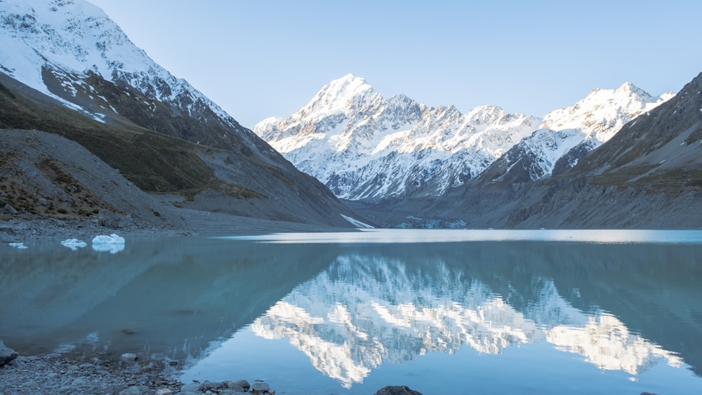 a mountain range is reflected in the still water of a lake