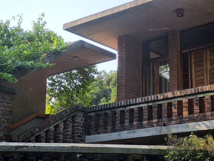 A sleek masonry garden room surrounded by lush greenery, showcasing clean lines and earthy tones.