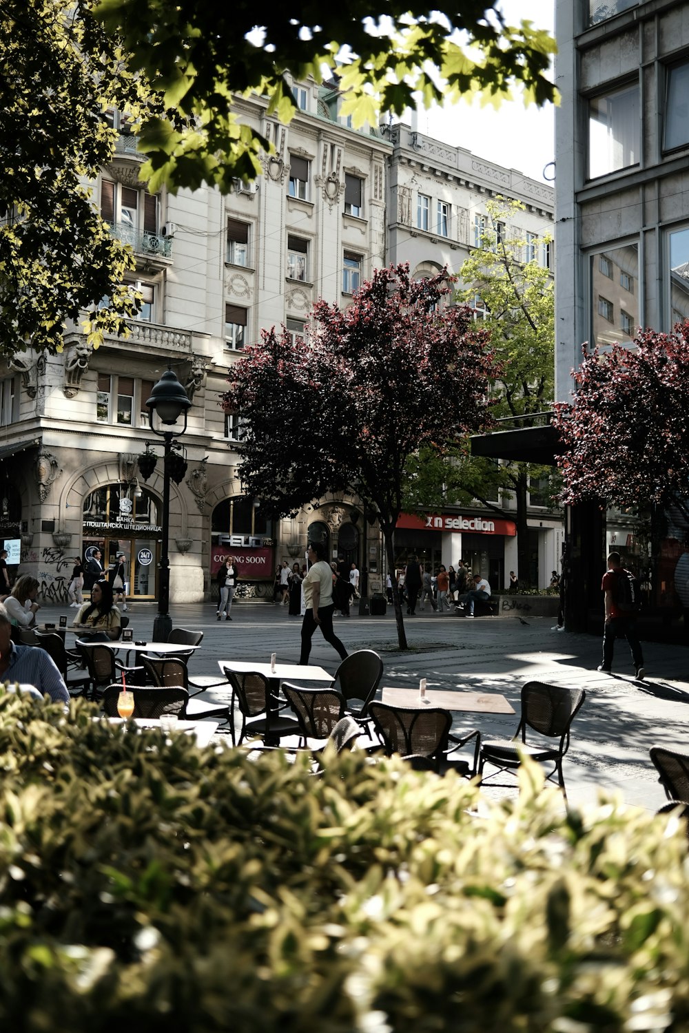 a group of people walking down a street next to tall buildings