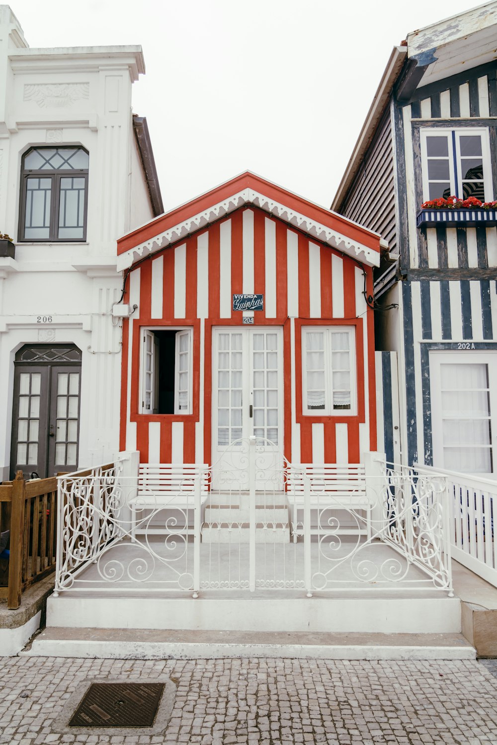 a red and white striped house with a white fence