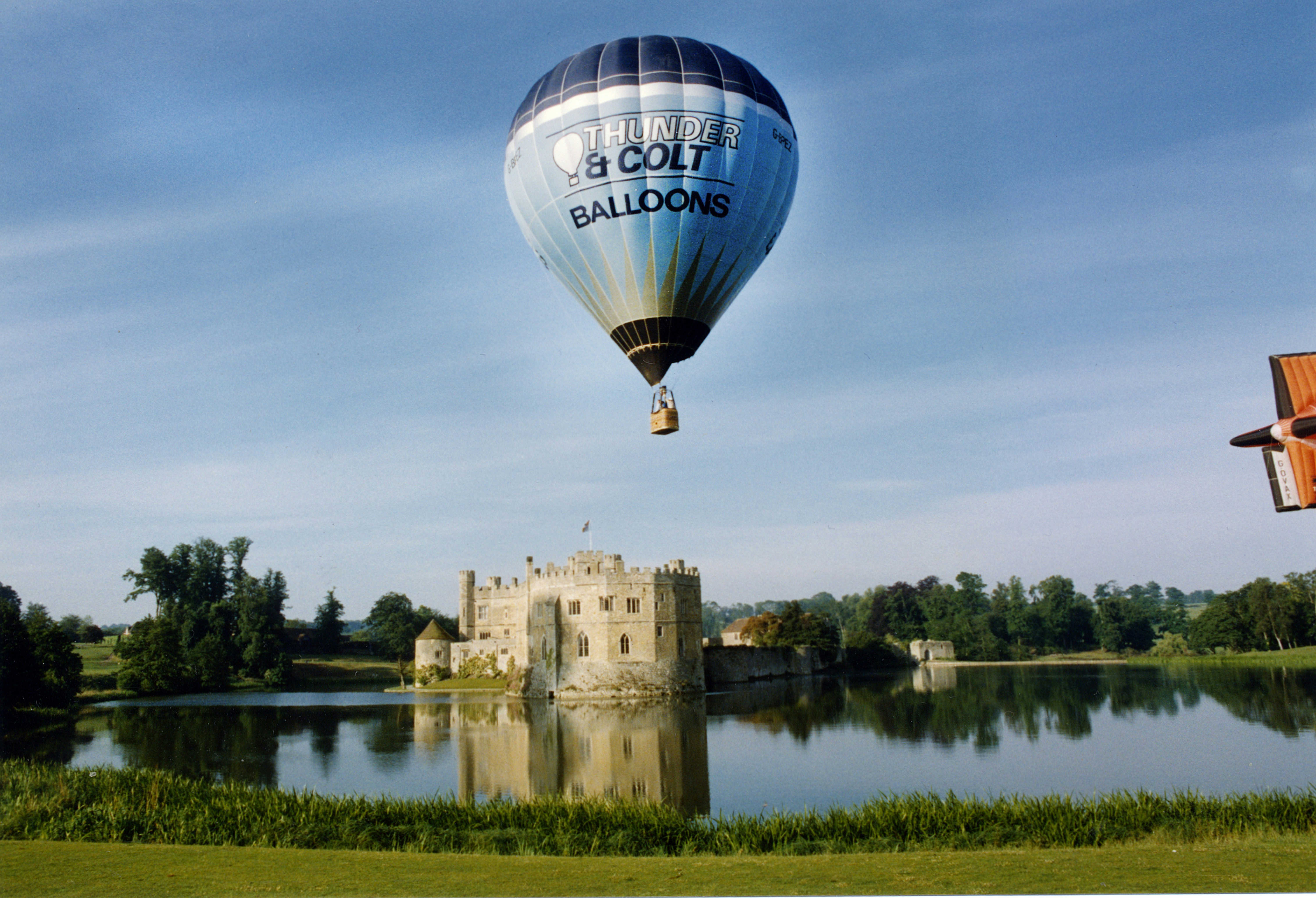 a hot air balloon flying over a lake