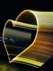 A soft gold abstract heart glowing gently against a warm beige background.