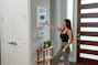 A smiling woman in a modern living room, interacting with a smart home control panel.