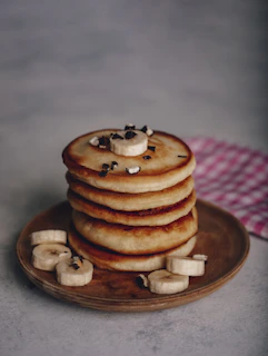 Bright and colorful display of assorted mini hotcakes with banana, Nutella, and nuts on a cheerful pastel plate.