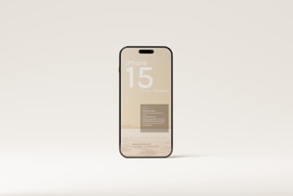 A smartphone with a clear, minimalist design appears to be the focus. The screen displays text, including 'iPhone 15 mockups,' and other smaller print. It is set against a neutral background, highlighting the device's sleek and modern aesthetics.