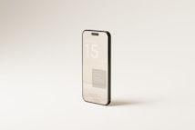 A smartphone stands upright against a minimalistic, light-colored background. The sleek design of the phone features a prominent display showing 'iPhone 15' in large text.