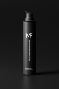 A sleek black pump bottle with a matte finish stands against a dark background. The letters 'MF' are prominently displayed in white on the upper part of the bottle. Beneath it, in smaller white text, there is a description indicating 'slim & tall pump bottle mockups.' The overall aesthetic is minimalistic and elegant.