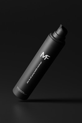 A sleek, matte black pump bottle with minimalistic design and white text reading 'MF' and 'slim & tall pump bottle mockups'. The bottle is elegantly styled against a dark background.