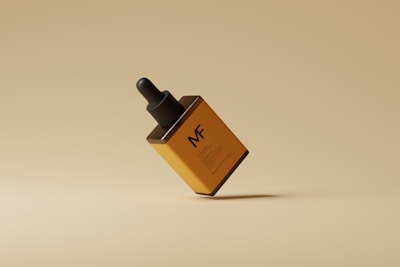 A minimalistic still life of a brown and orange dropper bottle with a black cap. The bottle appears to be floating against a monochromatic beige background, creating a clean and modern aesthetic.