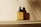 Elegant amber dropper bottle of Ecoembellish castor oil surrounded by fresh castor beans and green leaves on a beige background.
